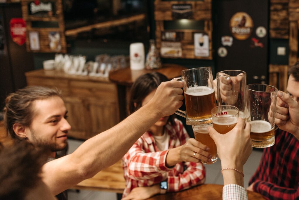 Venner som koser seg ute på pub om kvelden og drikker kalde øl i hyggelig belysning.