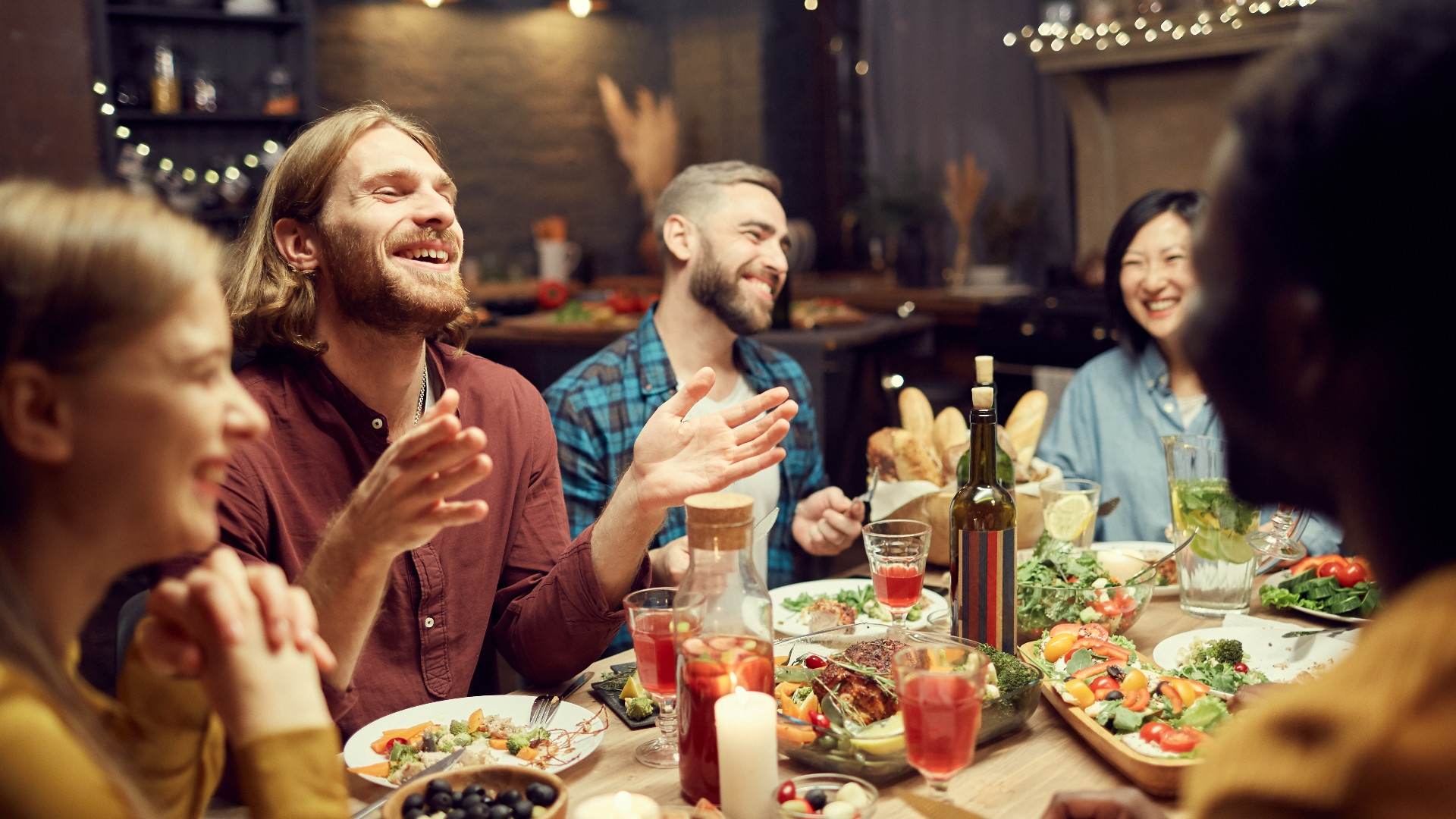 Venner ler og skåler rundt et pyntet julebord på en restaurant